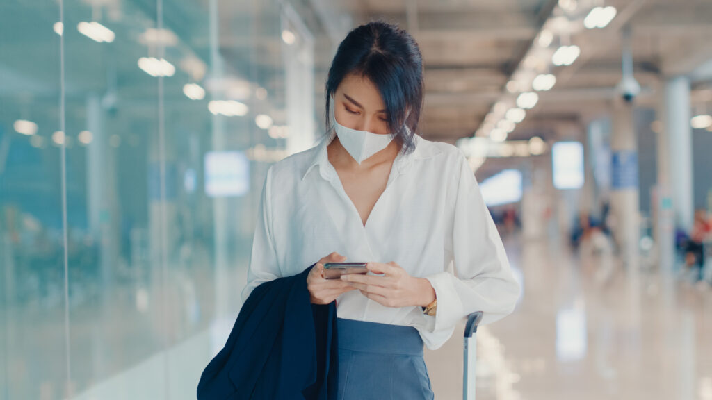 asian business girl using smartphone check boarding pass walking with luggage terminal domestic flight airport