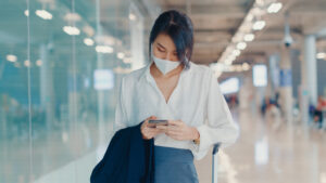 asian business girl using smartphone check boarding pass walking with luggage terminal domestic flight airport