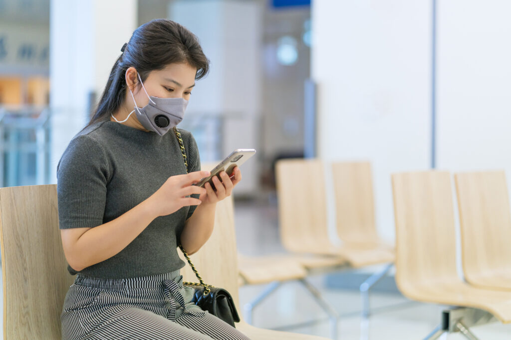 social distancing with asian female wear face mask virus protection waiting sit chair with space distance preventing virus spread
